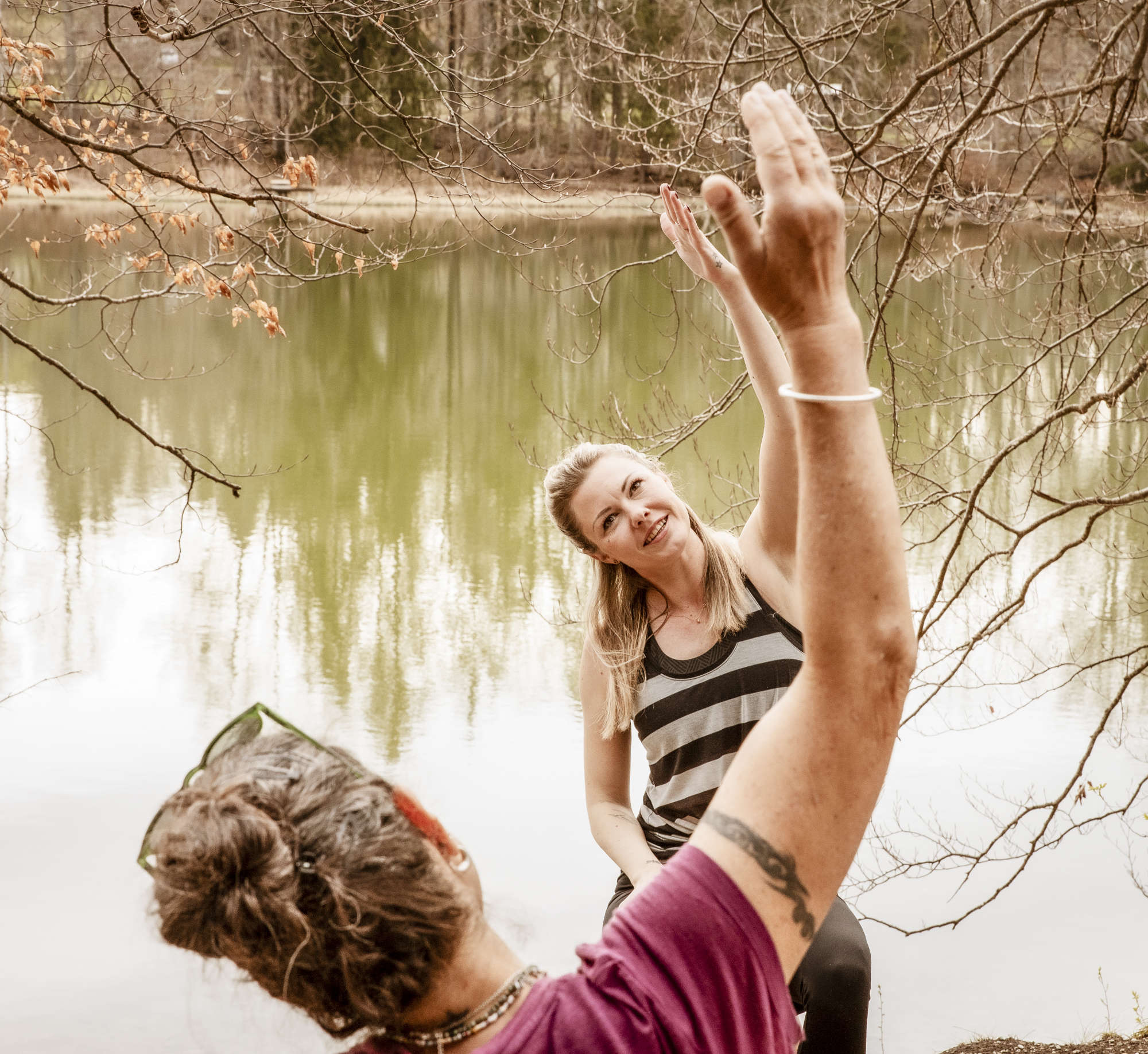 Yoga auf dem Stuhl zwei Personen bewegen ihren Arm nach oben vor einem See